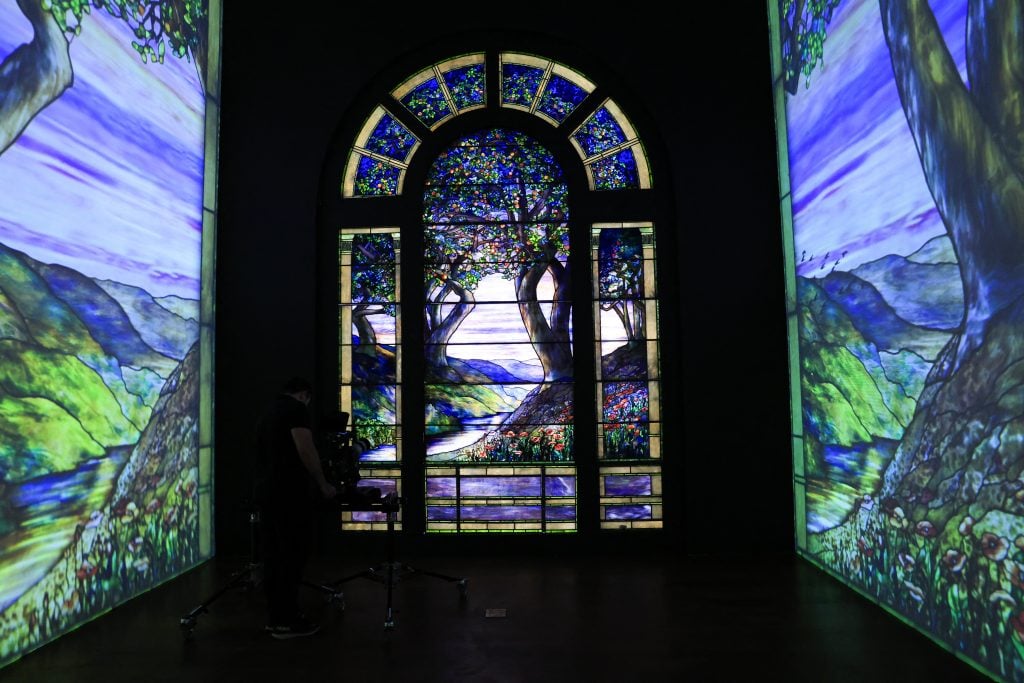 a darkly-lit installation of a blue, green, and purple hued stained glass window