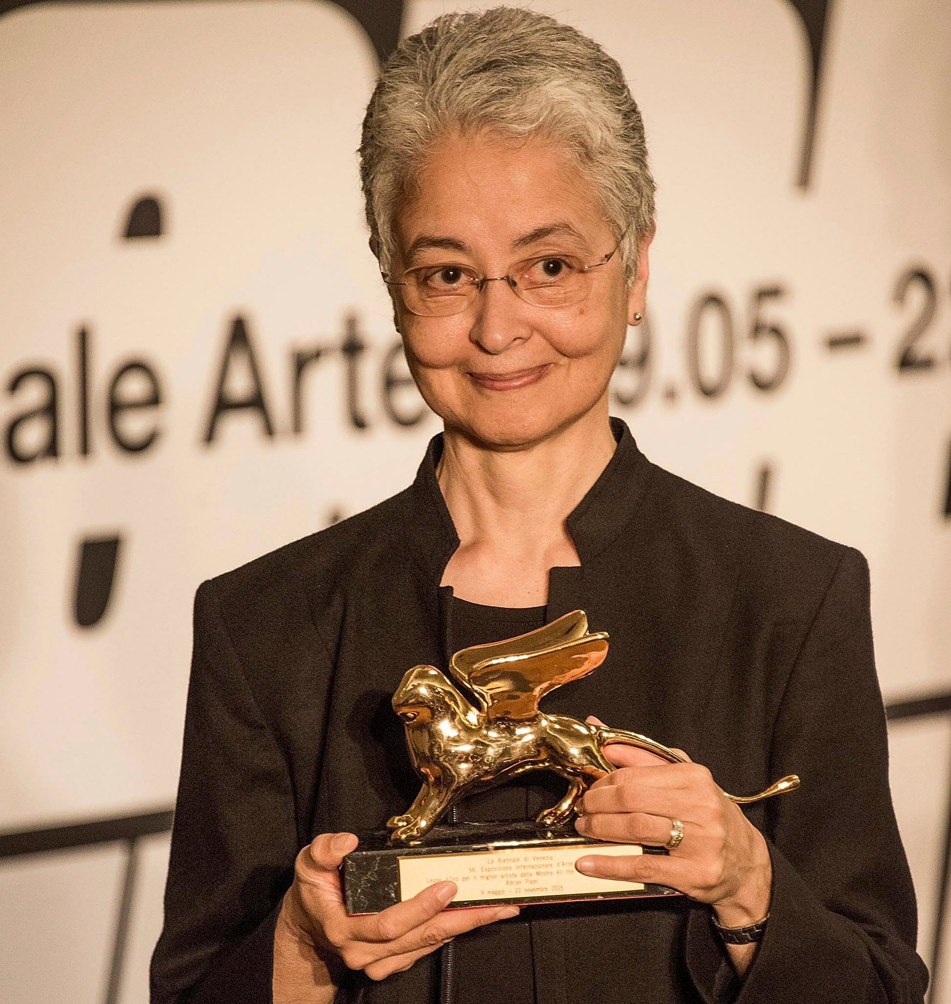 A woman holds a golden lion statue.