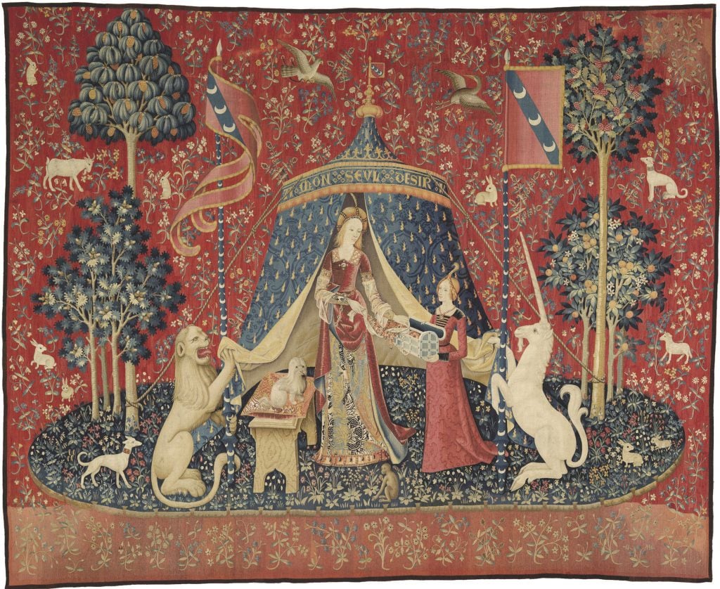 A medieval tapestry depicting a noblewoman with a lion, a unicorn, and detailed flora and fauna on a rich red background