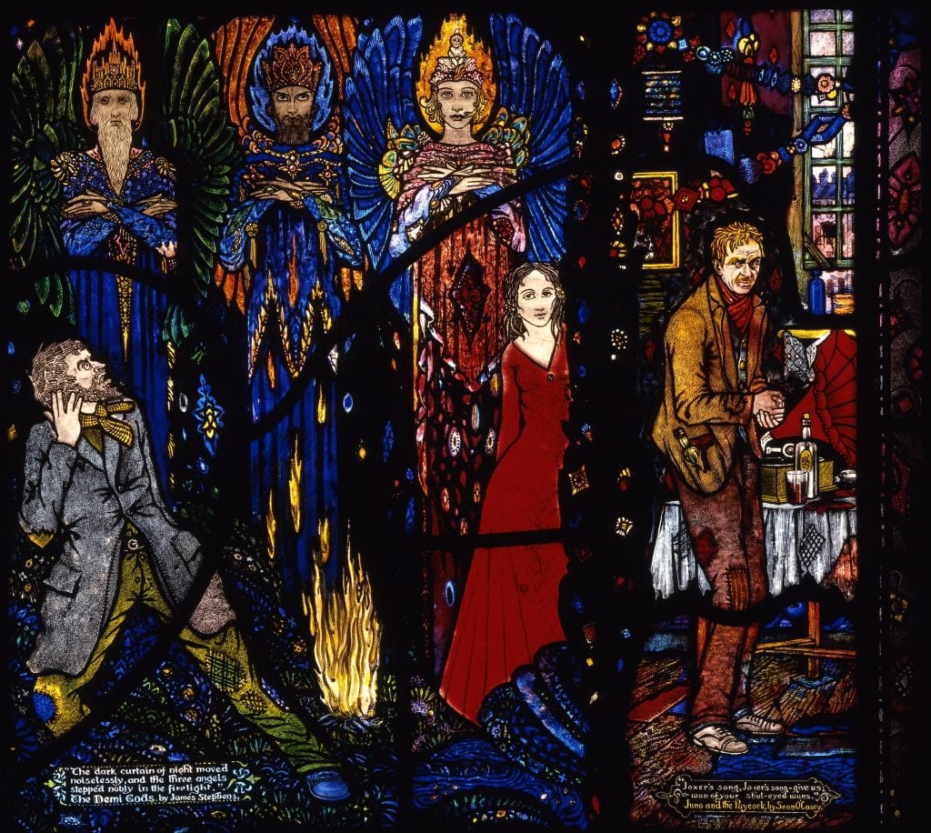 Harry Clarke, The Demi-Gods by James Stephens and Juno and the Paycock by Sean O'Casey from Harry Clarke Geneva Window (1926–30). A beautifully rendered stained glass window pane with three winged figures on the upper left corner, and a man staring at them in shock, next to a small campfire and a woman in a red dress. The figure on the bottom right is shabbily dressed and drinking liquor. 