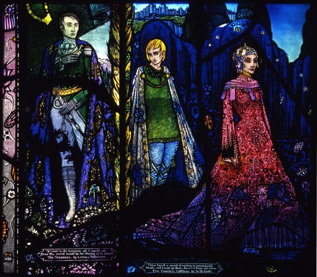 Harry Clarke, The Dreamers by Lennox Robinson and The Countess Cathleen by W.B. Yeats from Harry Clarke Geneva Window (1926–30). A beautifully rendered stained glass window of three figures: a man with a cloak and sword, a young man in a green tunic and white cloak, and a woman in a long red dress.