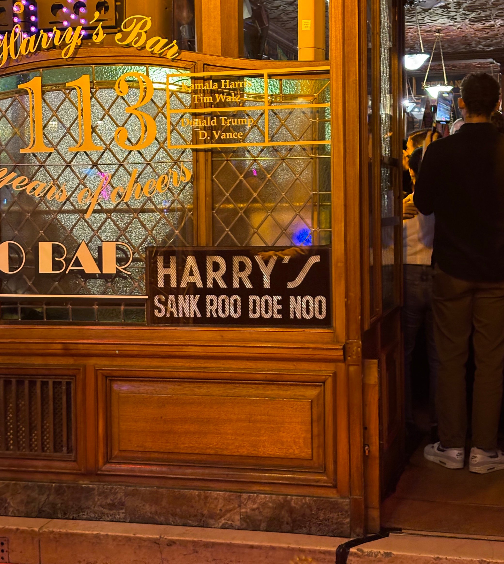 A wood-paneled bar is seen from outside. "Harry's," a sign reads.