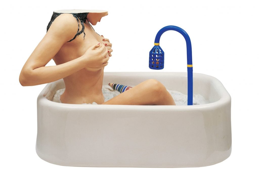 A sculptural artwork depicting a headless woman in a bathtub, holding her breasts. The figure features a vibrant blue faucet, with the entire scene set against a plain background.