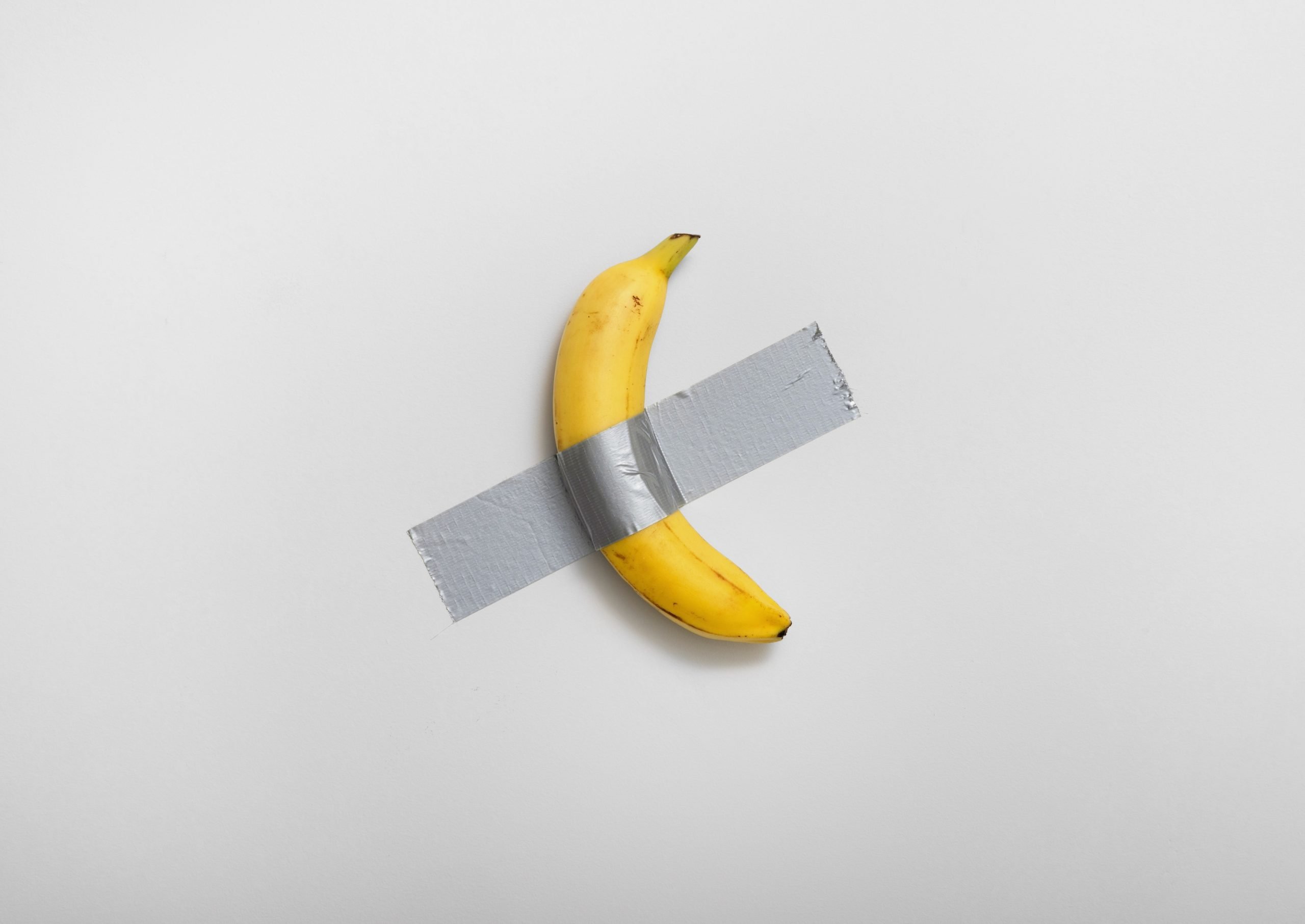 a banana duct taped to a white wall