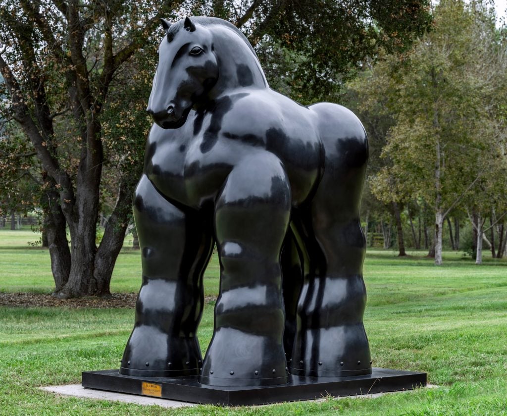 a large bronze horse statue is seen outside in a park