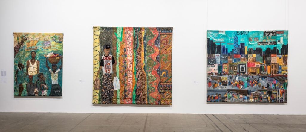 three large colorful semi-figurative textiles hanging on a white wall