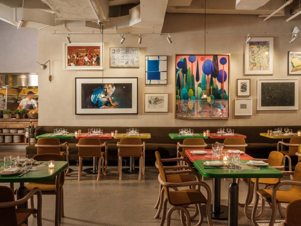 a restaurant wall is covered in paintings and photographs 