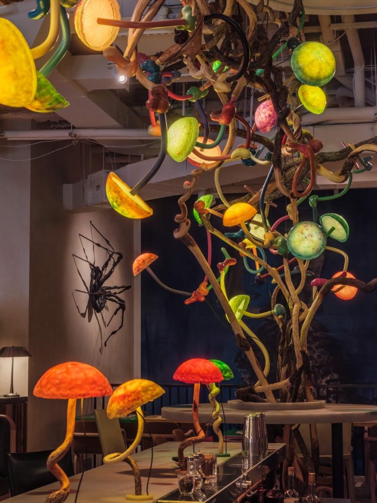 a spider sculpture is won a wall behind a bar modeled after mushrooms 