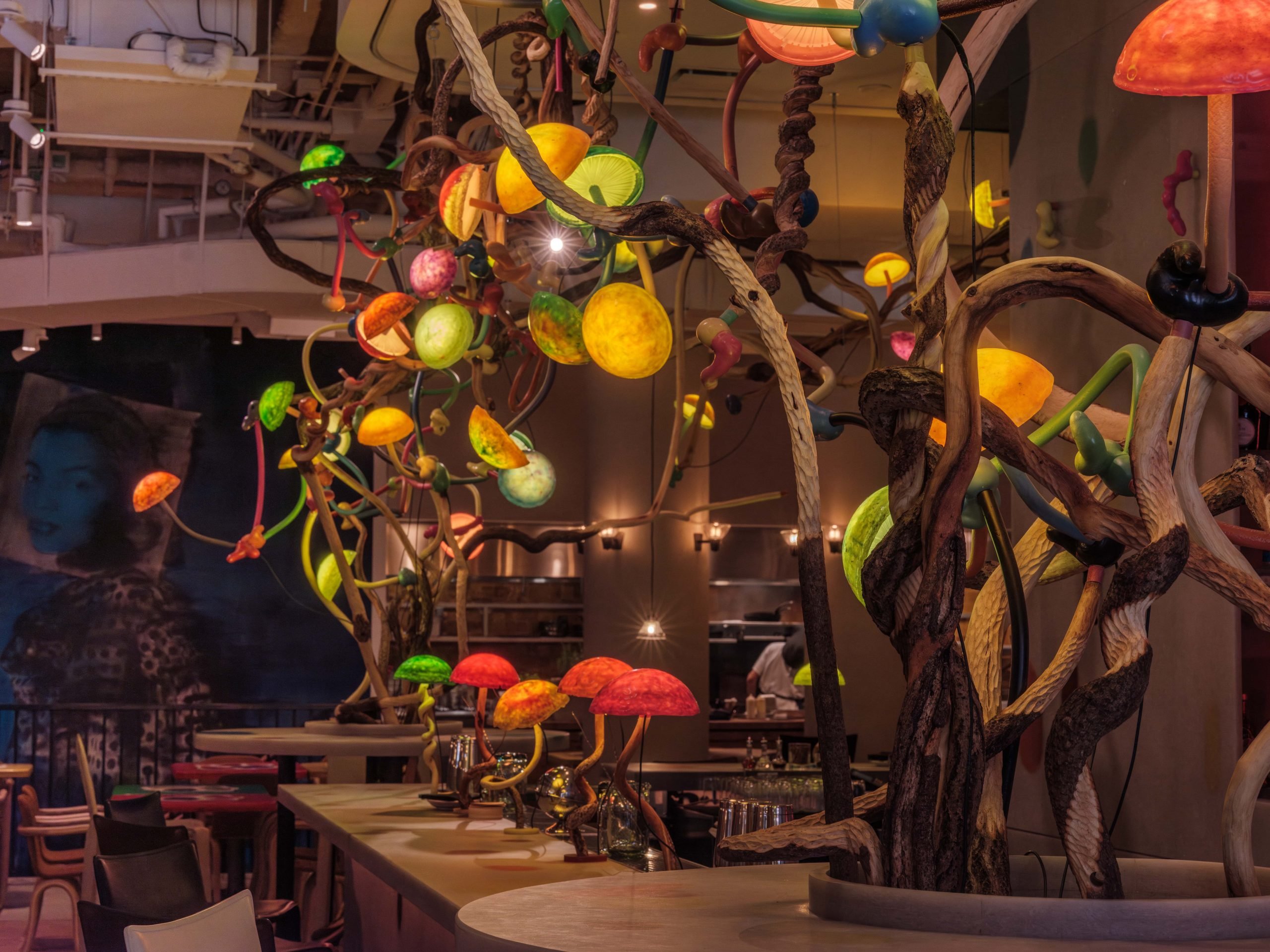 an artist designed chandelier resembles mushrooms and is illuminated in the dark and emanating various colors