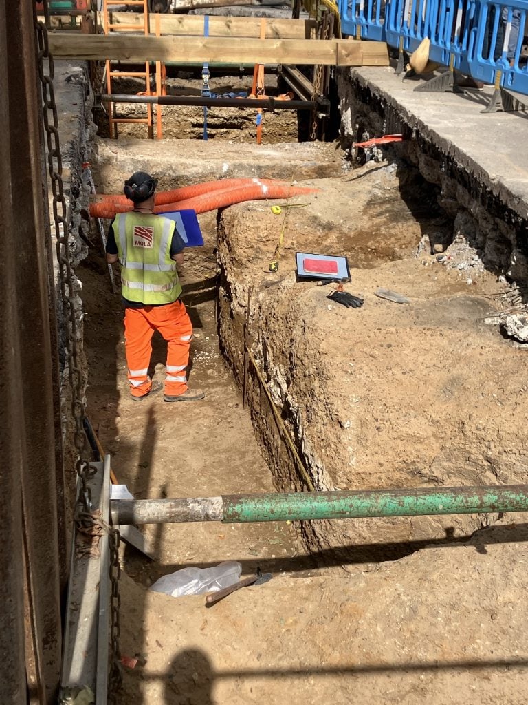 A construction worker stands near the remains of an ancient Roman road under a modern London street