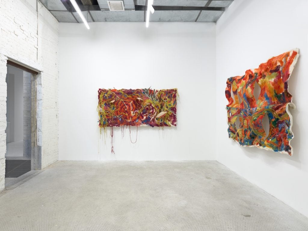 two colorful tapestries hang in a white room