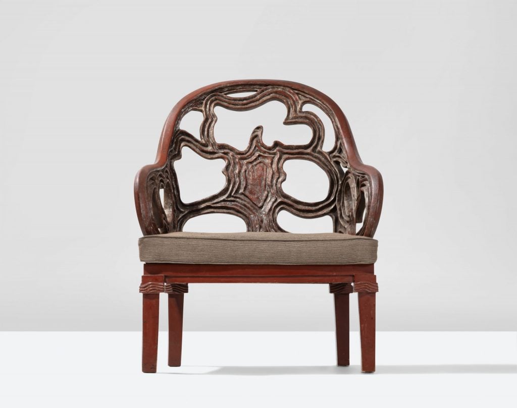 an armchair is intricately carved and set against a white background 