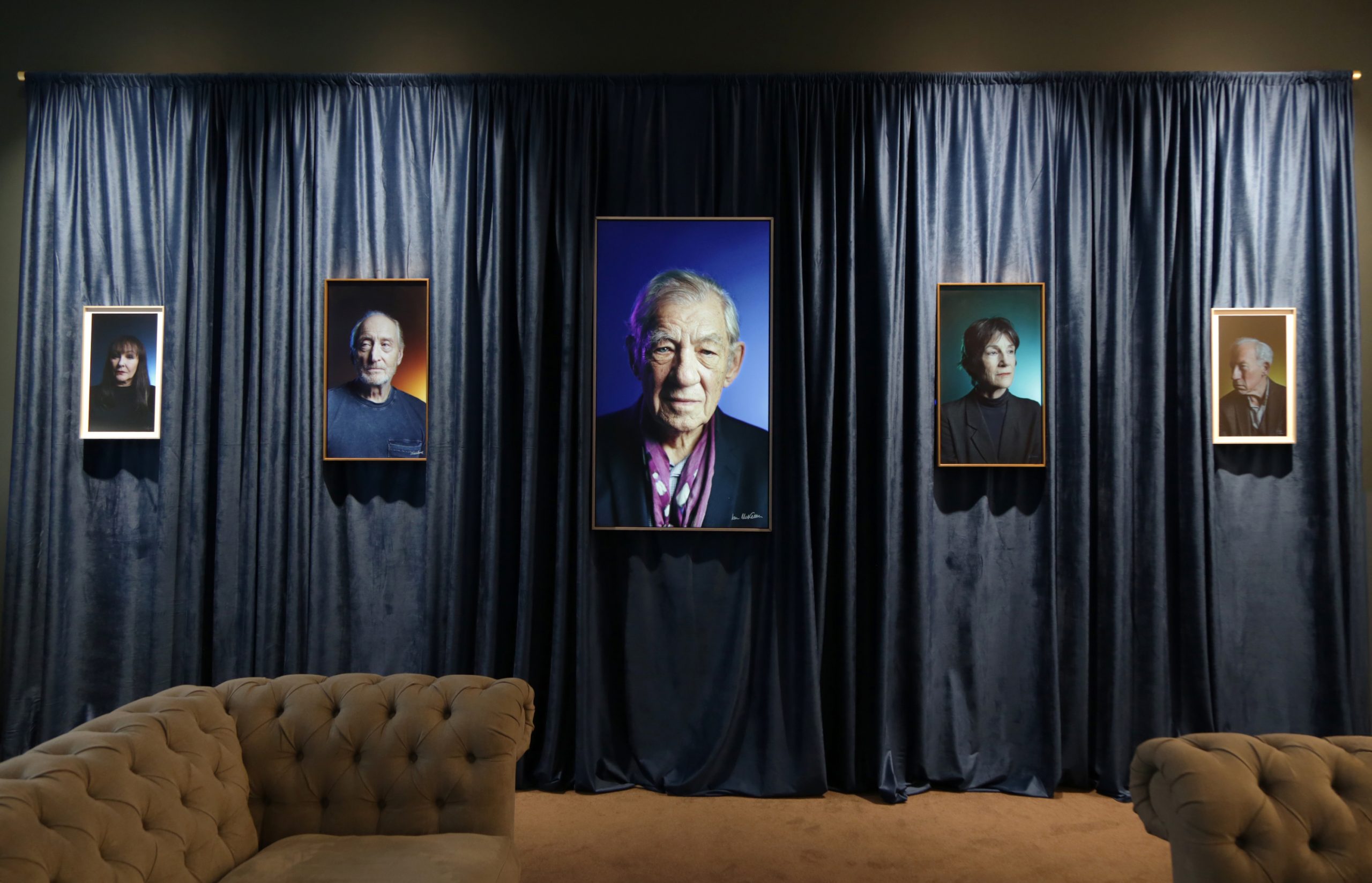 a curtained room with portraits left to right