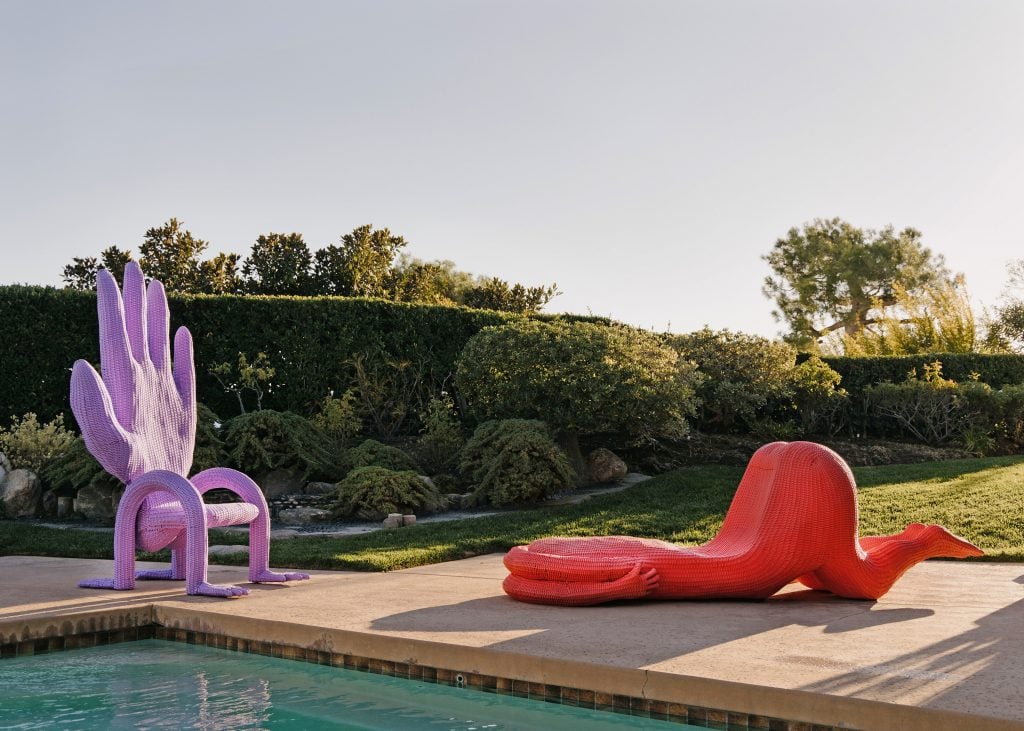 an outdoor pool seen with colorful handicapped chair and body shaped lounger 