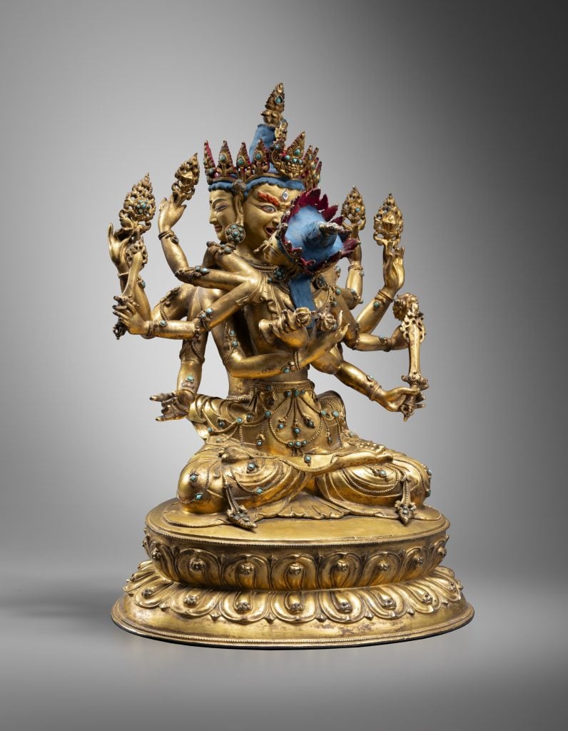 A bronze sculpture gilded in gold leaves depicting a tantric buddha with many arms