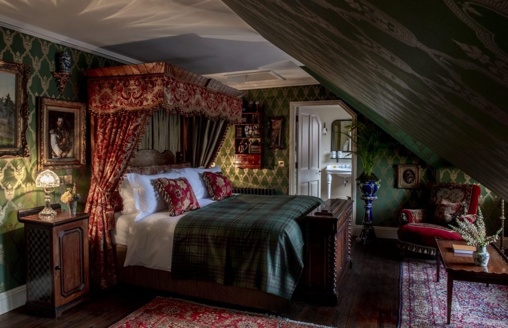 Luxurious bedroom with tartan bedding, ornate canopy, and Victorian-style decor.