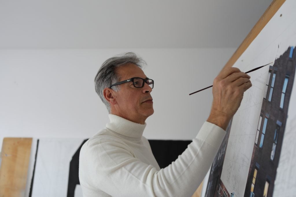 Portrait photo of artist Bertand Meniel in the midst of painting a work.