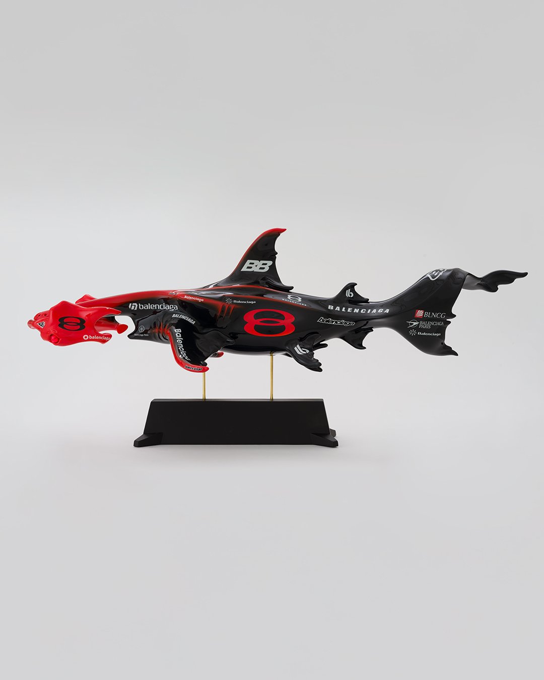 A photograph of a red and black Hammerhead shark made from Formula 1 car parts on an all white background.