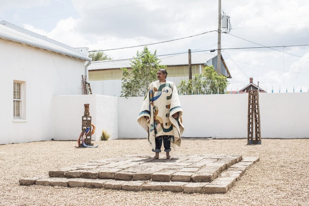 A man in a colorful poncho standing on an arrangement of stone bricks