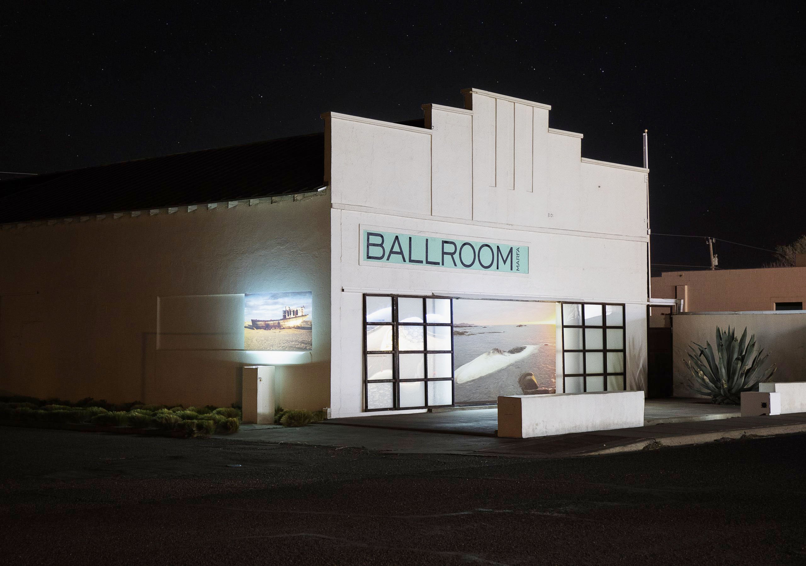 The exterior of a squat Art Deco-style building with the painted sign "Ballroom," as seen at night