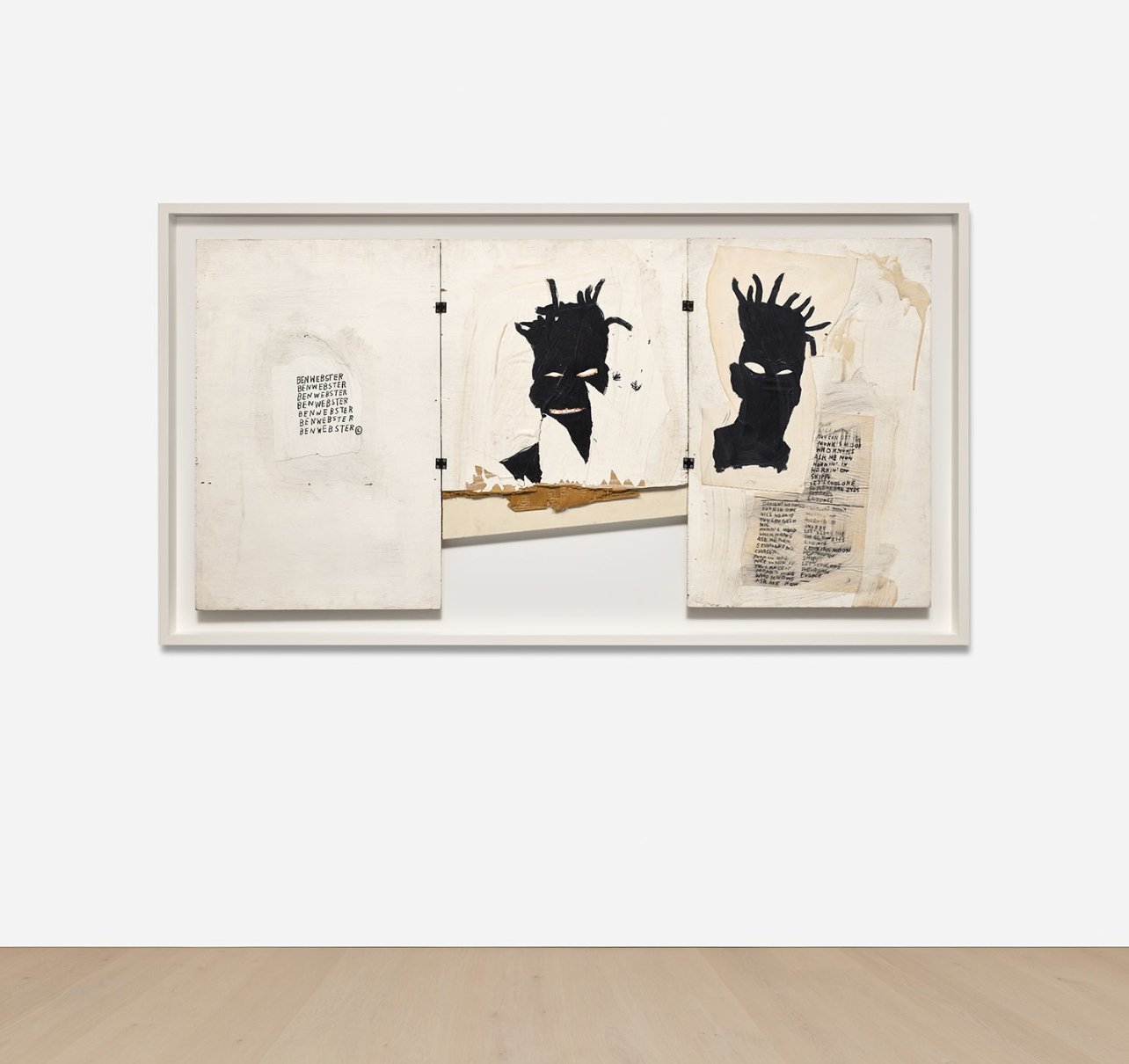 A painting of three white panels hangs on a wall, showing two Black men