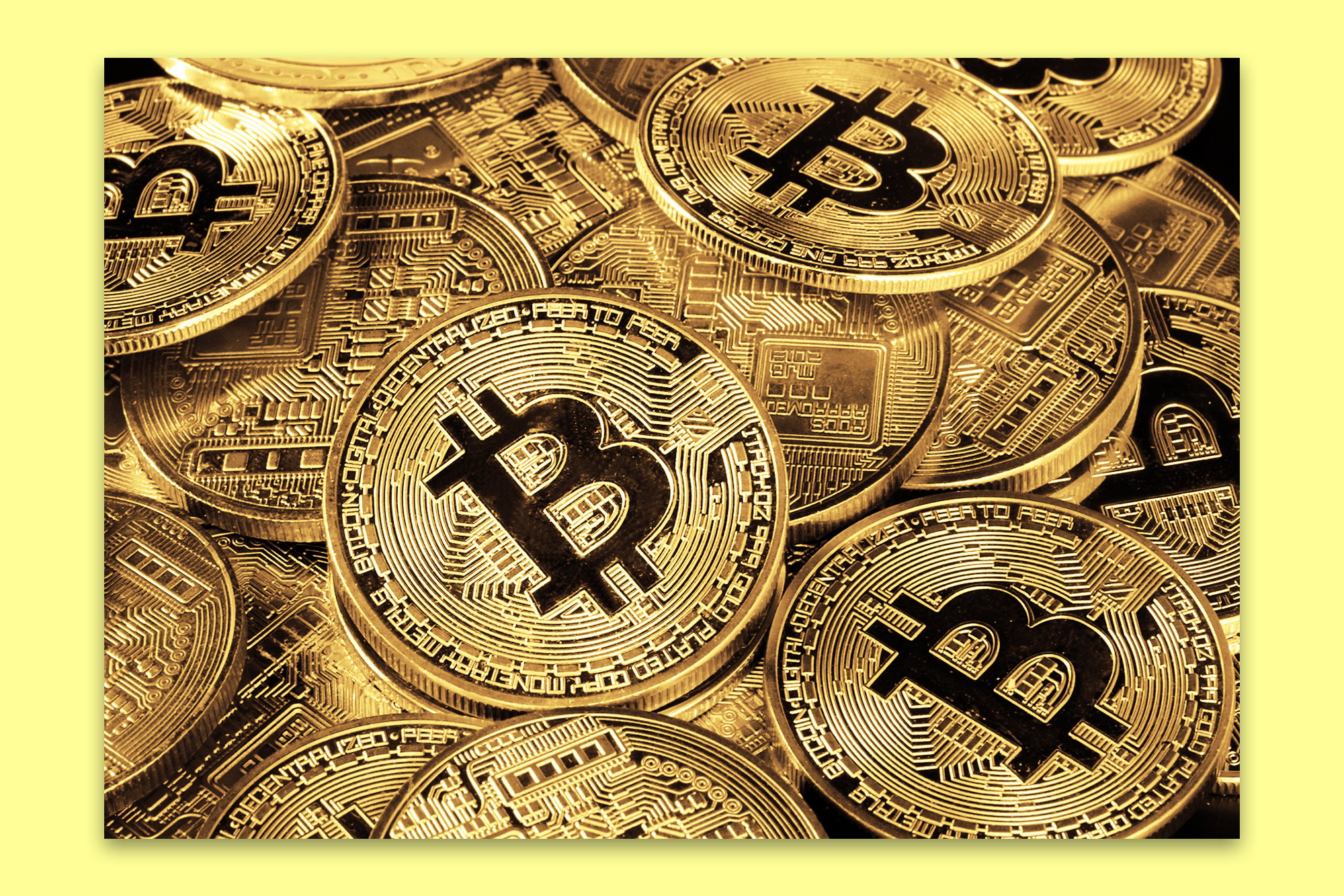 A close-up image of several gold-colored Bitcoin coins stacked together, showcasing the iconic Bitcoin logo and intricate circuit-like details.