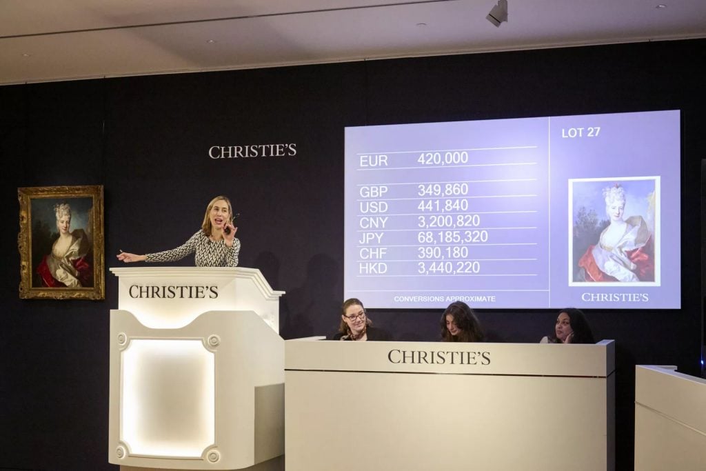 an auctioneer presides over the sale of a portrait of a woman