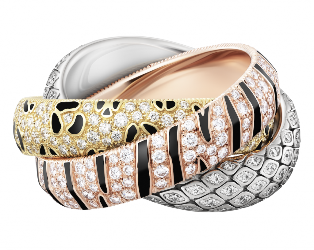 A photograph of a ring intertwining three different colored, jewel-encrusted bands all featuring a different animal print.