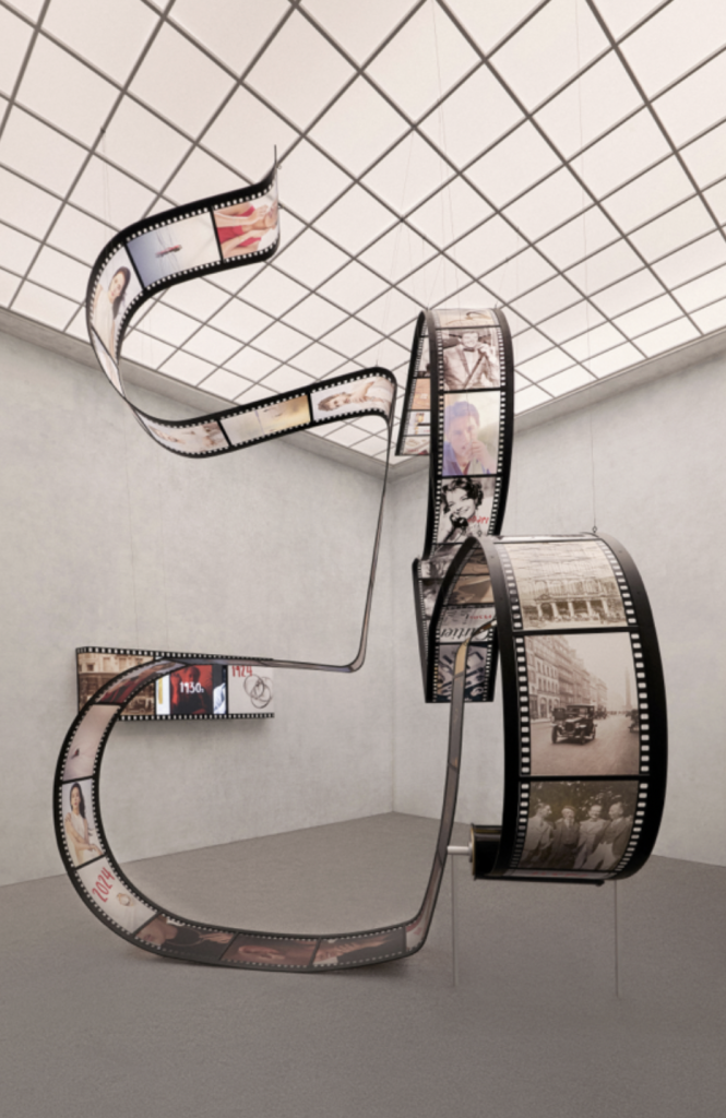 A photograph of a brightly lit room featuring a sculpture of an oversized film strip depicting celebrities throughout the ages.