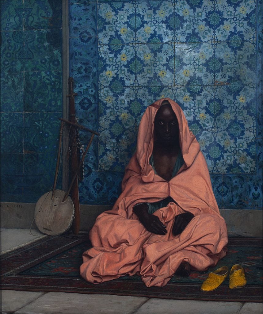 Jean-Léon Gérôme painting depicting a black bard sitting on the ground on a mat swathed in salmon pink robe in front of a bright blue tiled wall beside a stringed instrument. 