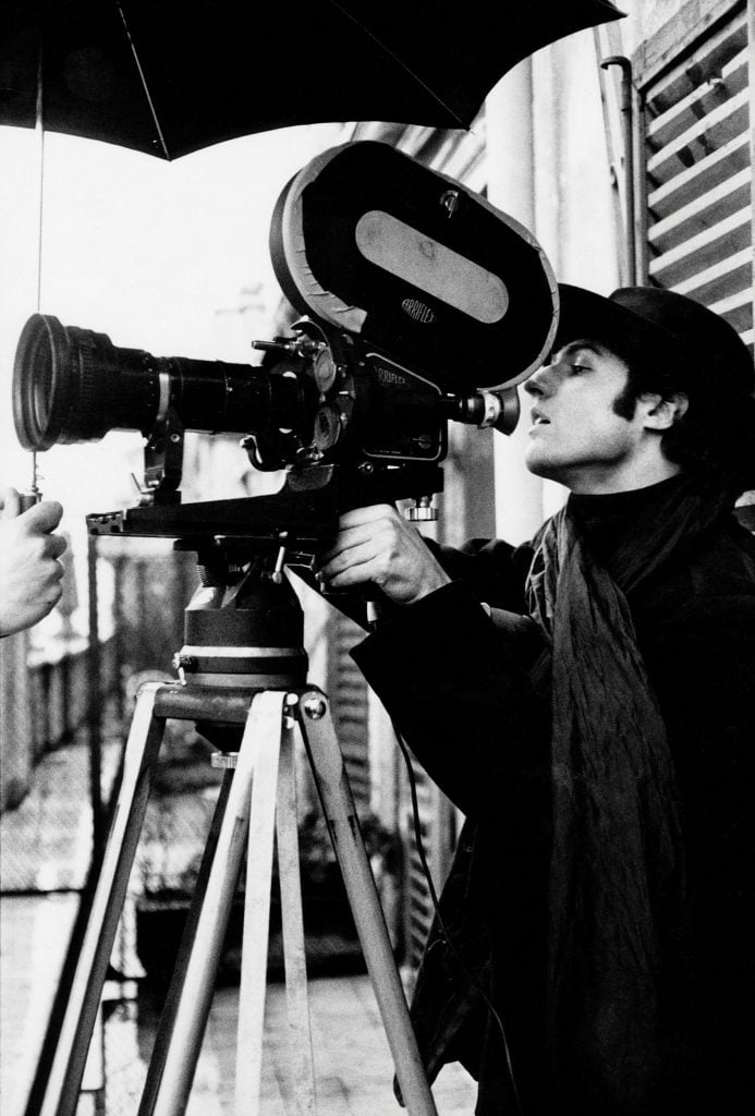 A man standing behind a film camera