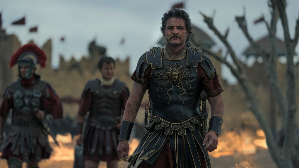 A film still of Pedro Pascal marching away from a firey battlefield in Gladiator II.