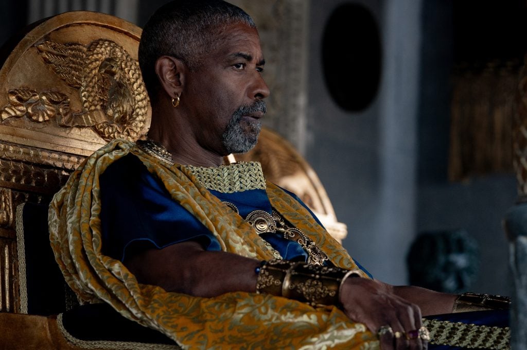 A film still of a seated Denzel Washington in the movie Gladiator II,