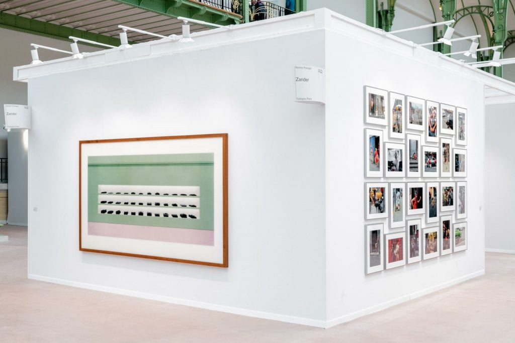 an installation view of an art fair booth with several photos hung on either wall