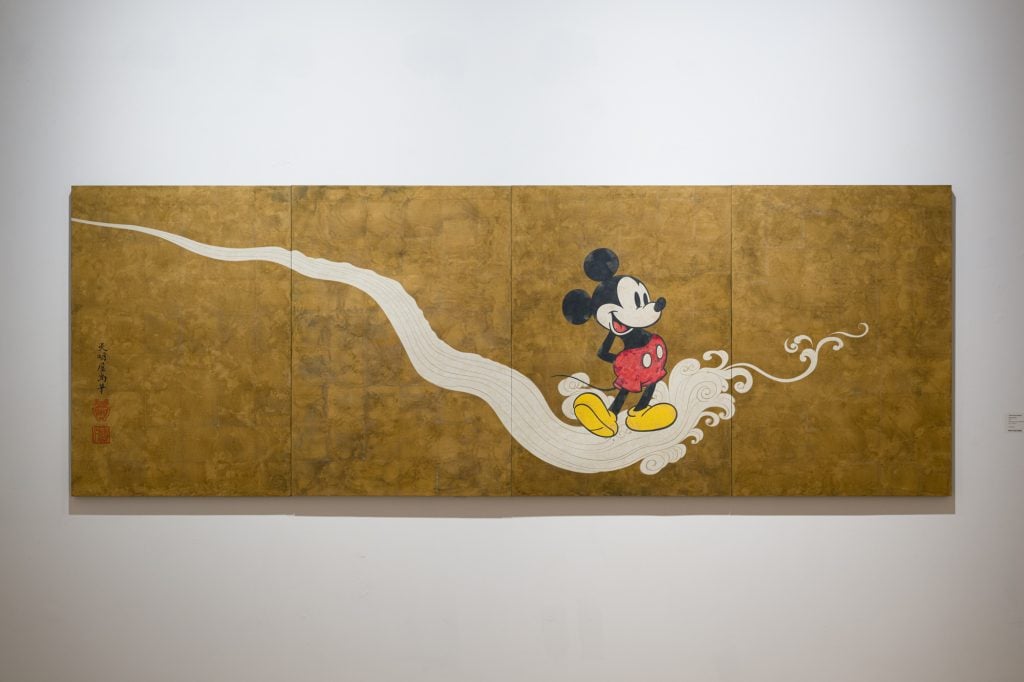 A long painting with an ochre gold ground and a swirling white path in which the Disney character of Mickey Mouse is walking.