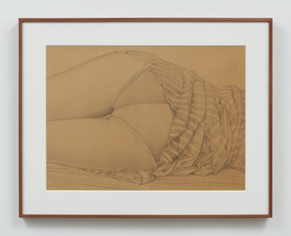 A photograph of a framed pencil sketch depicting the panty-clad backside of a prone woman.