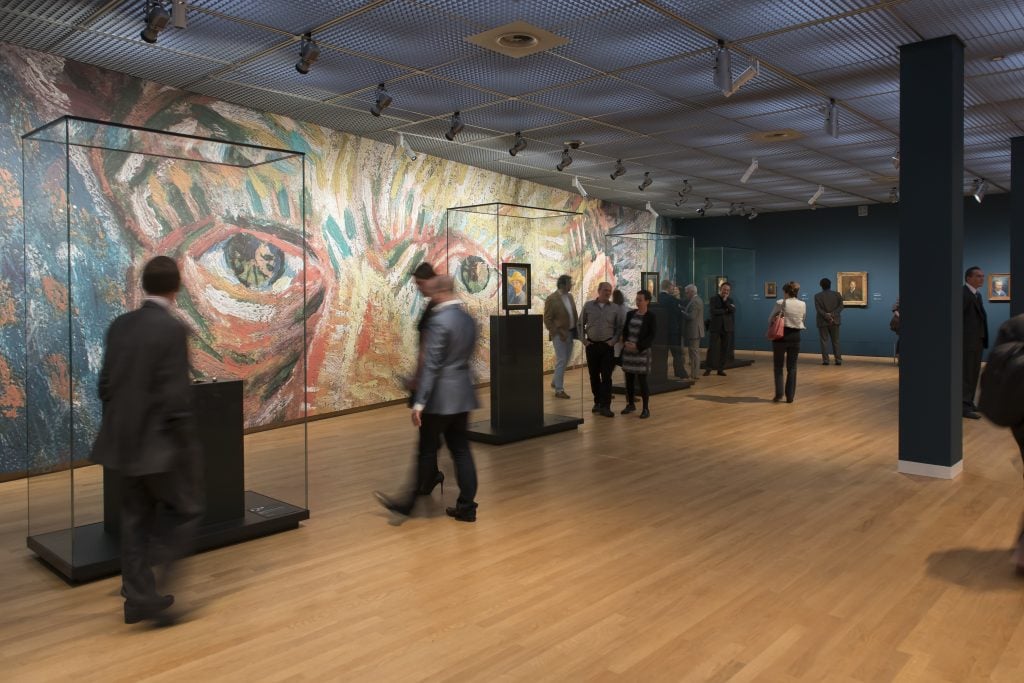 visitors in the Van Gogh museum look at works on plinths