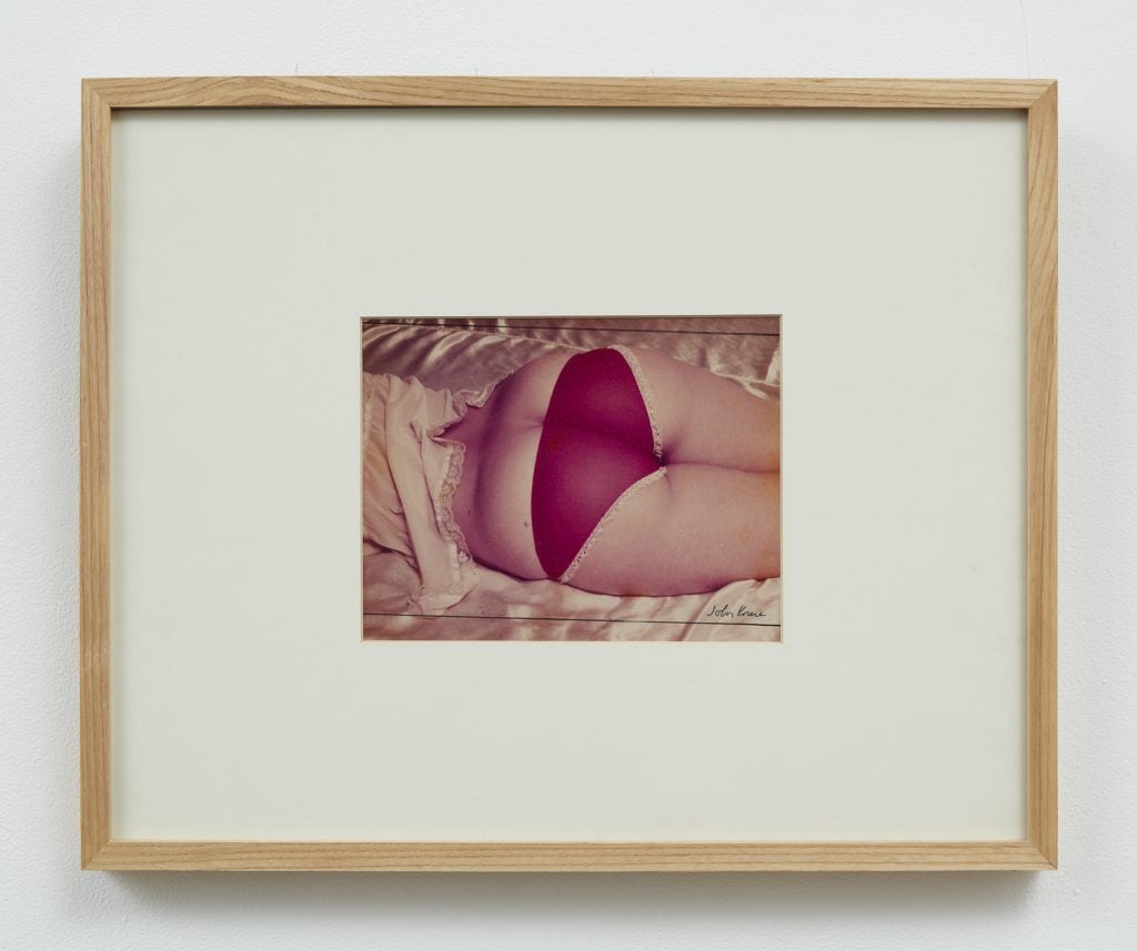 A photograph of a framed photo depicting a prone woman wearing red panties.