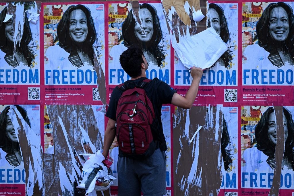 A man tears down a political poster that says FREEDOM