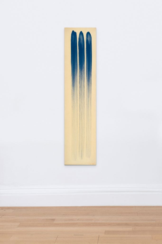 Artnet Auctions Post-War and Contemporary Art sale lot by Lee Ufan of a vertical rectangular canvas in yellowish white with three vertical streaks of deep blue that fade as the brush ran out of paint toward the bottom.