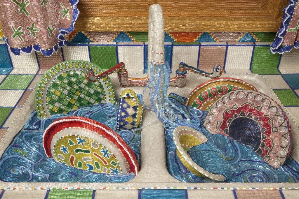 A kitchen sink full of water and colorful plates lined with colorful beads, 