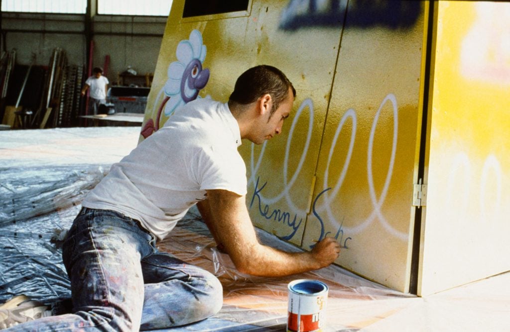 a man is on the ground signing his name to an amusement park ride that he is panting 