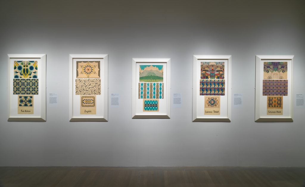 "Mary Sully: Native Modern" at the Metropolitan Museum of Art, New York. Five of the artists' three-panel colored pencil drawings, with their symmetrical geometric designs inspired by Modernist art and Native American traditions, are on view in a white-walled museum gallery, lit by spotlights. 