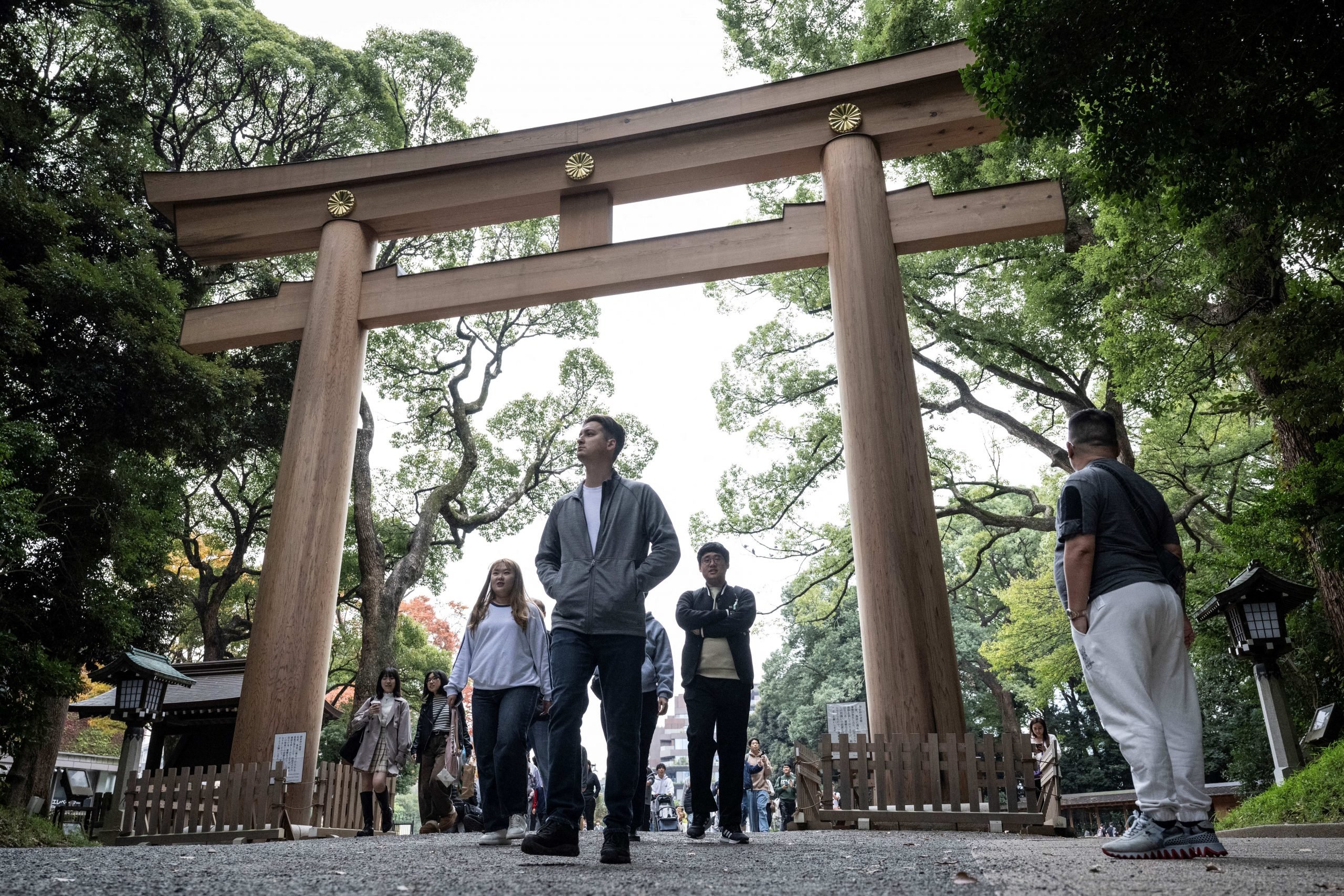 People walk past a Torii gate at Meiji shrine in Tokyo