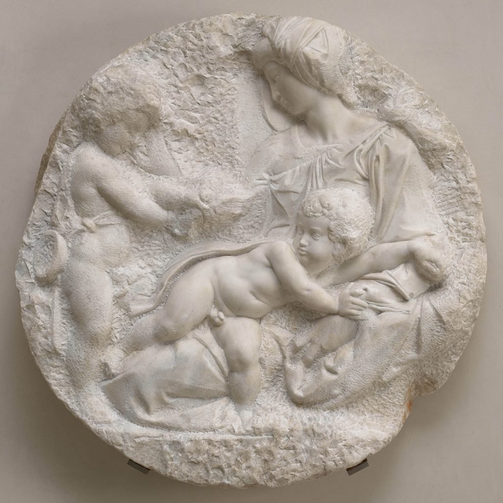 A large white carved stone showing a mother and two infant children.