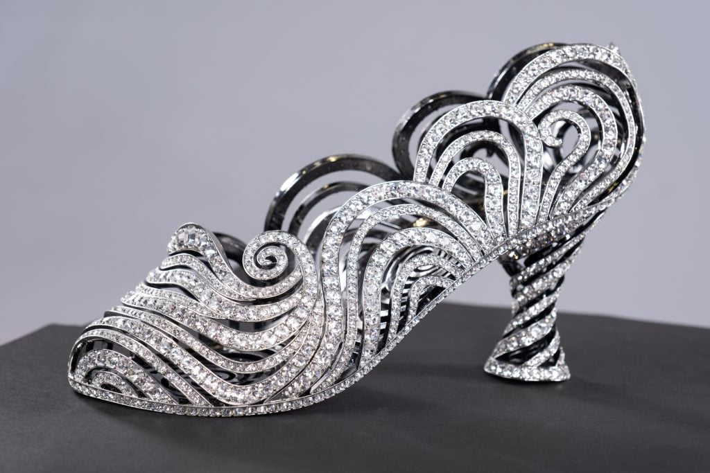 A photograph of an ornate shoe crafted from silver and rhinestones in swirling shapes.