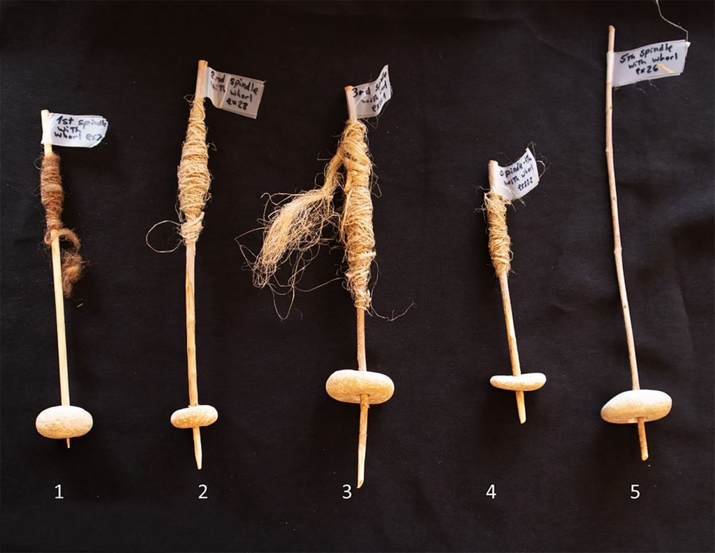 five sticks threaded through a pebble sit on a black background