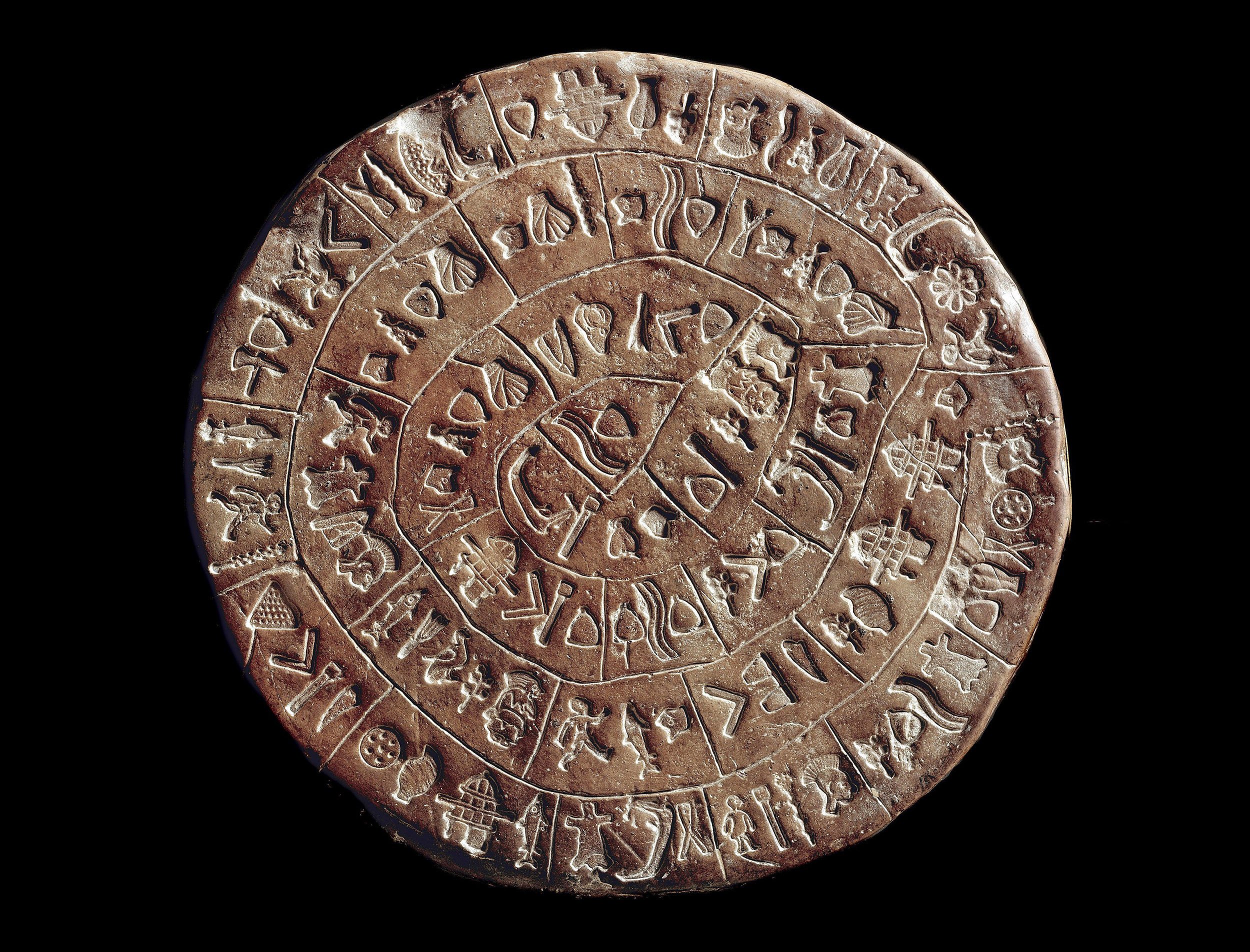 An image of the Phaistos Disc, an ancient circle clay dish with a spiral of hieroglyphics imprinted on both sides of the dish.