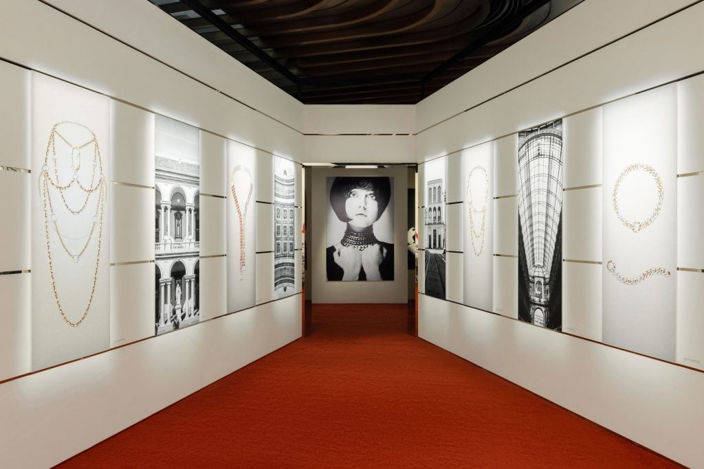 A red-carpeted white hallway lined with photos inside the Pomellato retrospective 