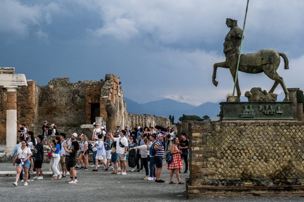 Visitors crowd around an open area at Pompeii